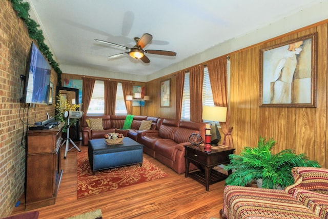 living area with brick wall, ceiling fan, and wood finished floors