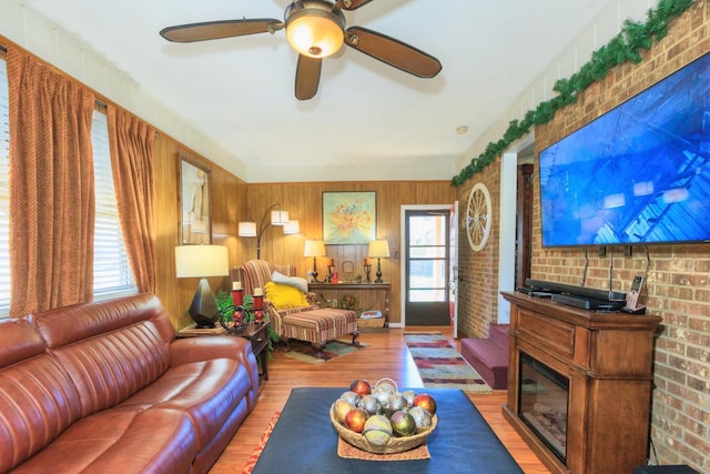 living room with ceiling fan, plenty of natural light, a glass covered fireplace, and wood finished floors