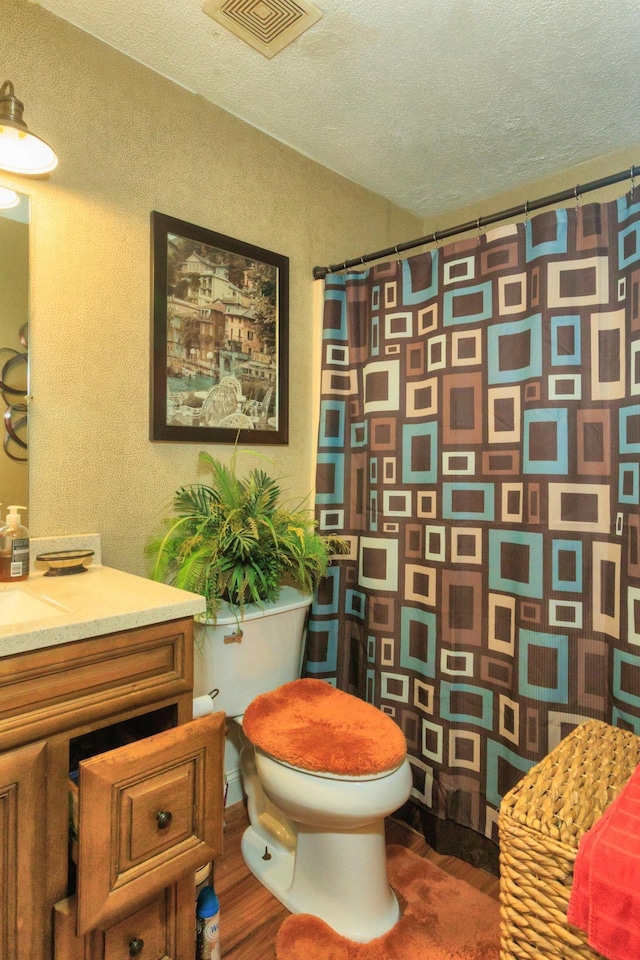 full bathroom with visible vents, toilet, curtained shower, a textured ceiling, and wood finished floors