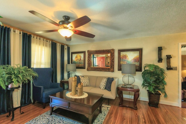 living room with a ceiling fan, wood finished floors, baseboards, and a textured ceiling