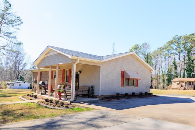 view of side of property with a yard, covered porch, and driveway