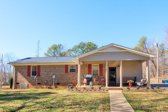 view of front facade with brick siding, covered porch, and a front lawn