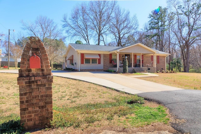 view of front of home featuring brick siding, covered porch, driveway, and a front lawn