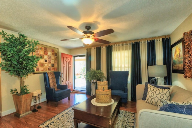 living room with ceiling fan, baseboards, a textured ceiling, and wood finished floors