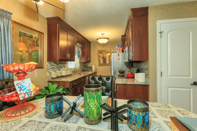 kitchen with a sink, stainless steel appliances, backsplash, and a textured ceiling