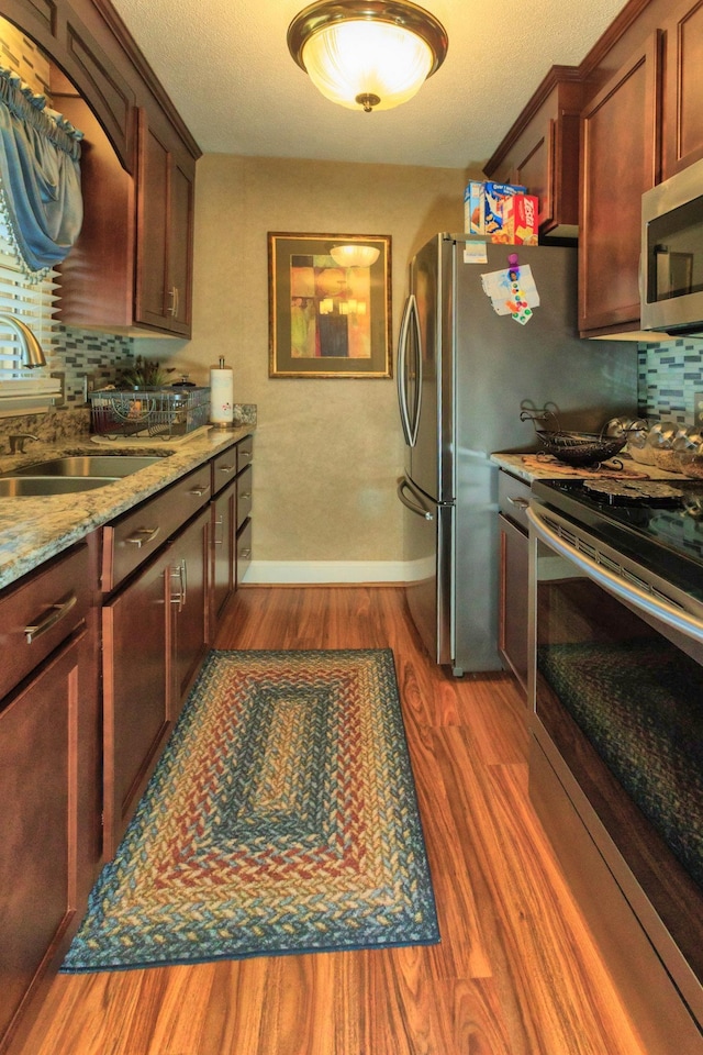 kitchen featuring dark wood-type flooring, a sink, stainless steel microwave, tasteful backsplash, and stove