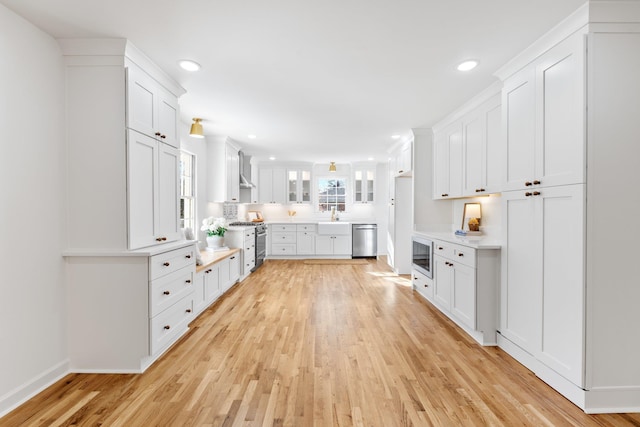 kitchen featuring a sink, light wood-style floors, white cabinetry, and stainless steel appliances