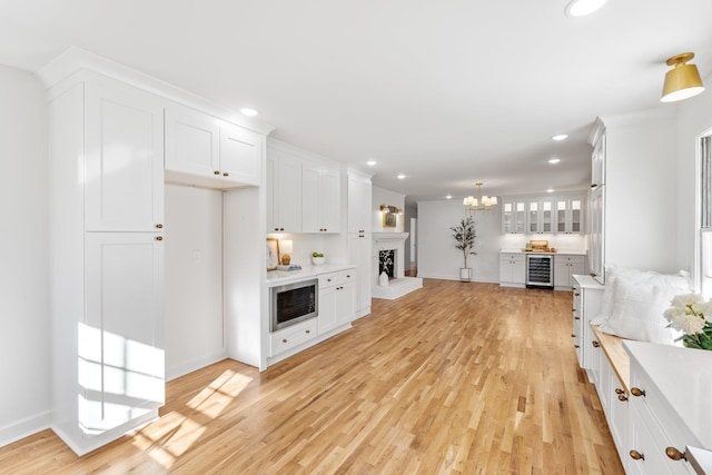 living room with wine cooler, a notable chandelier, light wood-style floors, and recessed lighting