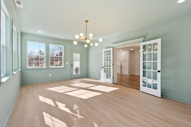 spare room with crown molding, a notable chandelier, wood finished floors, and visible vents