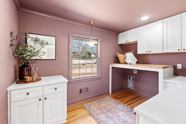 kitchen with visible vents, light wood-style floors, crown molding, and light countertops