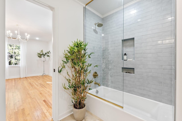 bathroom with ornamental molding, wood finished floors, tub / shower combination, baseboards, and a chandelier