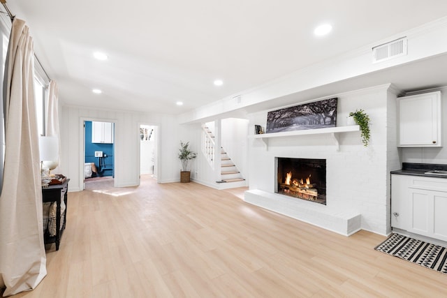 living room featuring visible vents, stairs, recessed lighting, a fireplace, and light wood-style floors