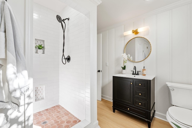 bathroom featuring vanity, toilet, wood finished floors, and tiled shower