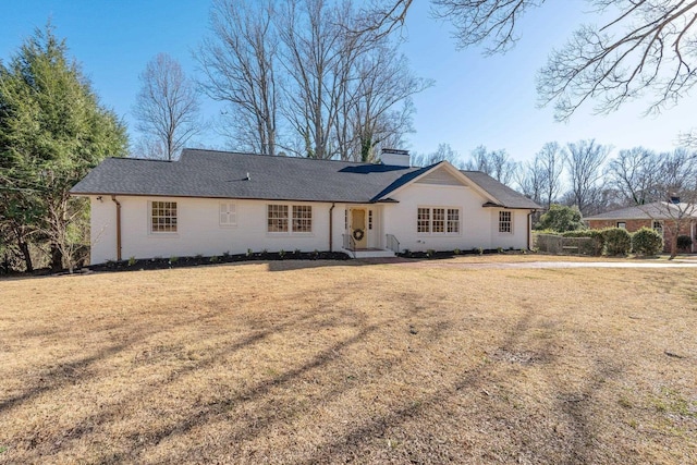 back of house featuring a lawn and a chimney