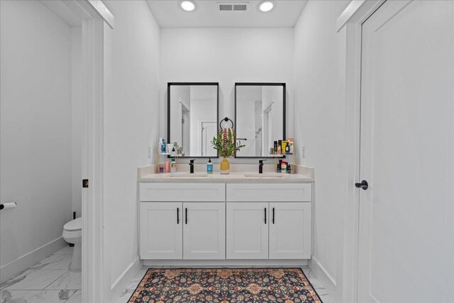 full bath with visible vents, toilet, baseboards, and a sink