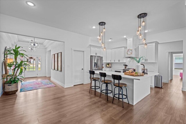kitchen featuring tasteful backsplash, wall chimney range hood, a breakfast bar, light countertops, and stainless steel appliances