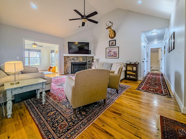 living room with light wood-style flooring, a fireplace, high vaulted ceiling, and ceiling fan