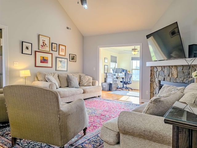 living room featuring wood finished floors, visible vents, high vaulted ceiling, a fireplace, and ceiling fan