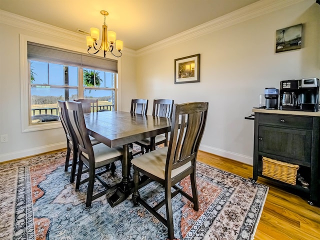 dining area featuring a notable chandelier, wood finished floors, baseboards, and ornamental molding