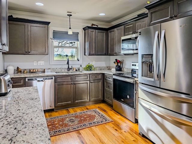 kitchen with visible vents, light wood-style flooring, a sink, stainless steel appliances, and dark brown cabinetry