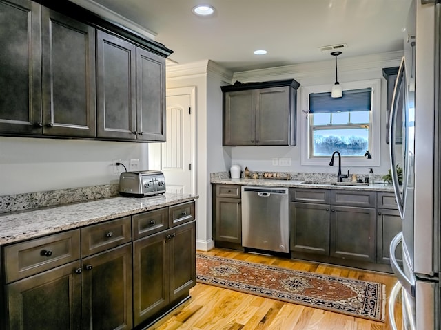 kitchen with visible vents, a sink, light stone counters, appliances with stainless steel finishes, and light wood finished floors