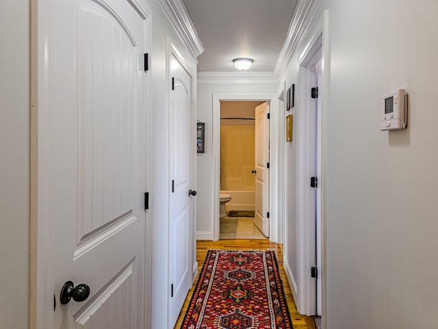 corridor featuring light wood-type flooring and ornamental molding