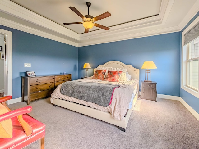 carpeted bedroom featuring a tray ceiling, baseboards, ceiling fan, and crown molding