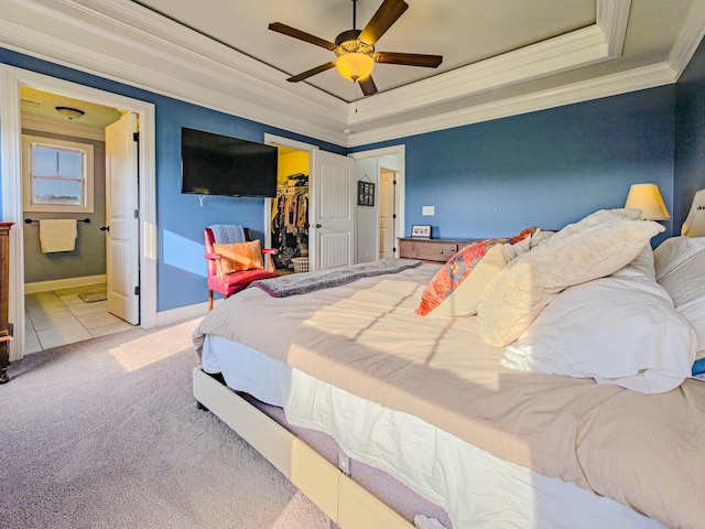 tiled bedroom featuring crown molding, a closet, a walk in closet, a raised ceiling, and carpet flooring