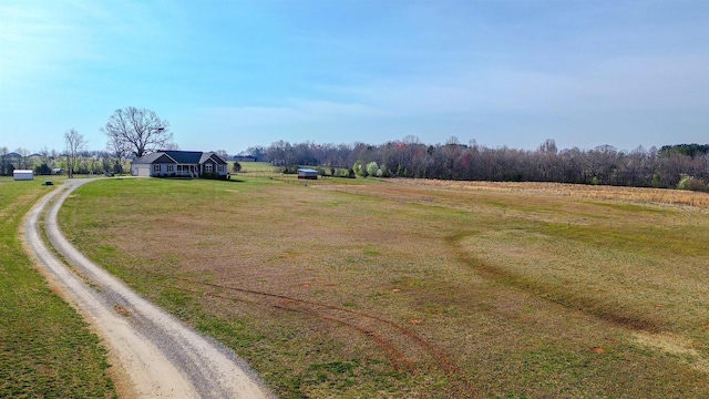 view of street with a rural view and dirt driveway