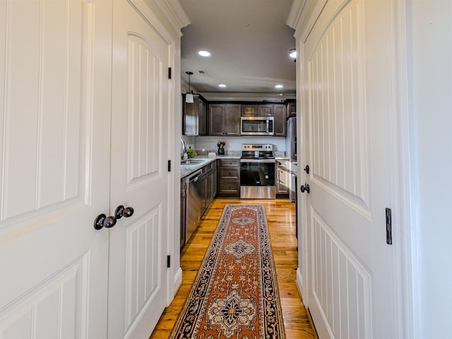 kitchen featuring recessed lighting, light wood-style floors, appliances with stainless steel finishes, dark brown cabinetry, and light countertops