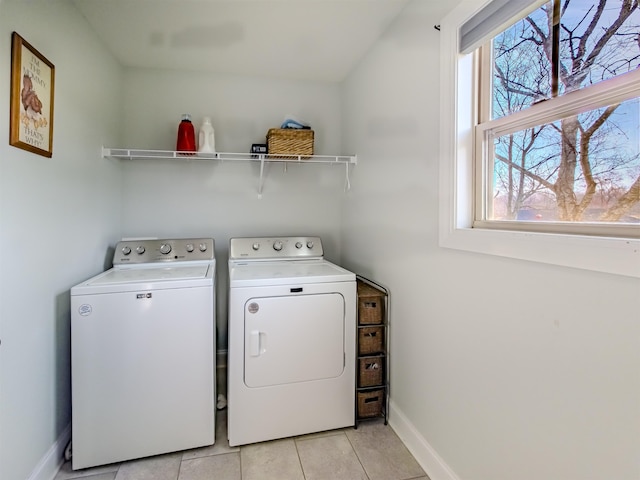 clothes washing area with baseboards, light tile patterned flooring, washing machine and dryer, and laundry area