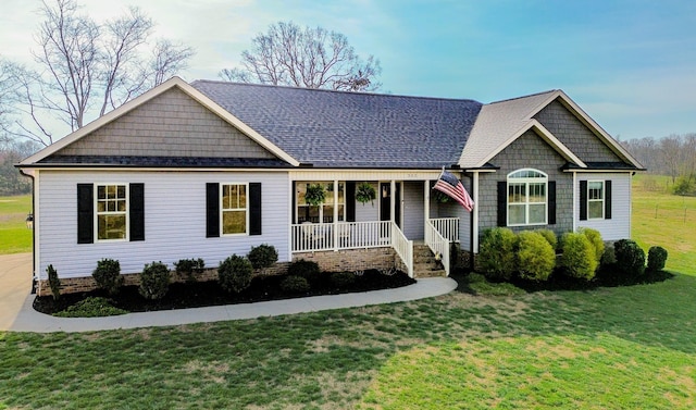 view of front of home with a porch, a front lawn, and roof with shingles