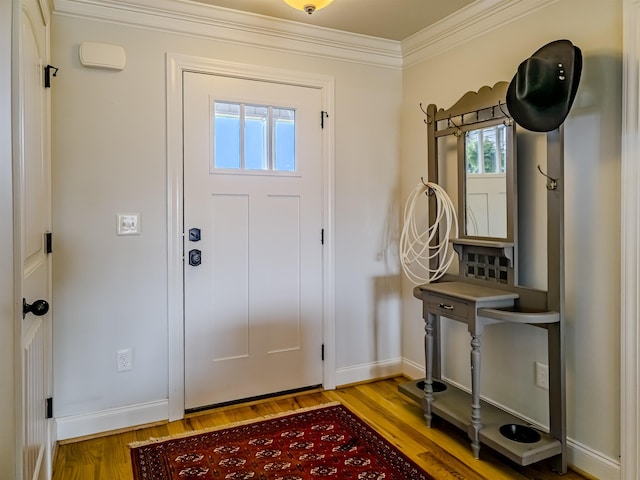 entryway featuring wood finished floors, baseboards, and ornamental molding