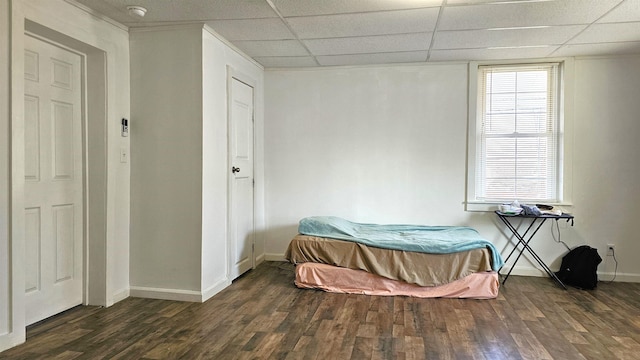 bedroom with baseboards, a paneled ceiling, and wood finished floors