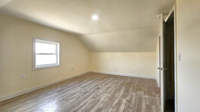 bonus room with baseboards, wood finished floors, and vaulted ceiling