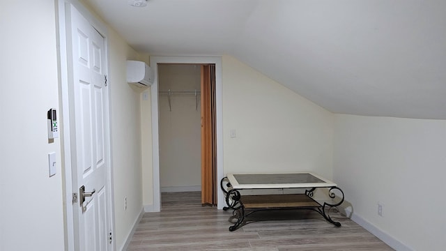 additional living space with vaulted ceiling, light wood-style floors, baseboards, and a wall mounted AC