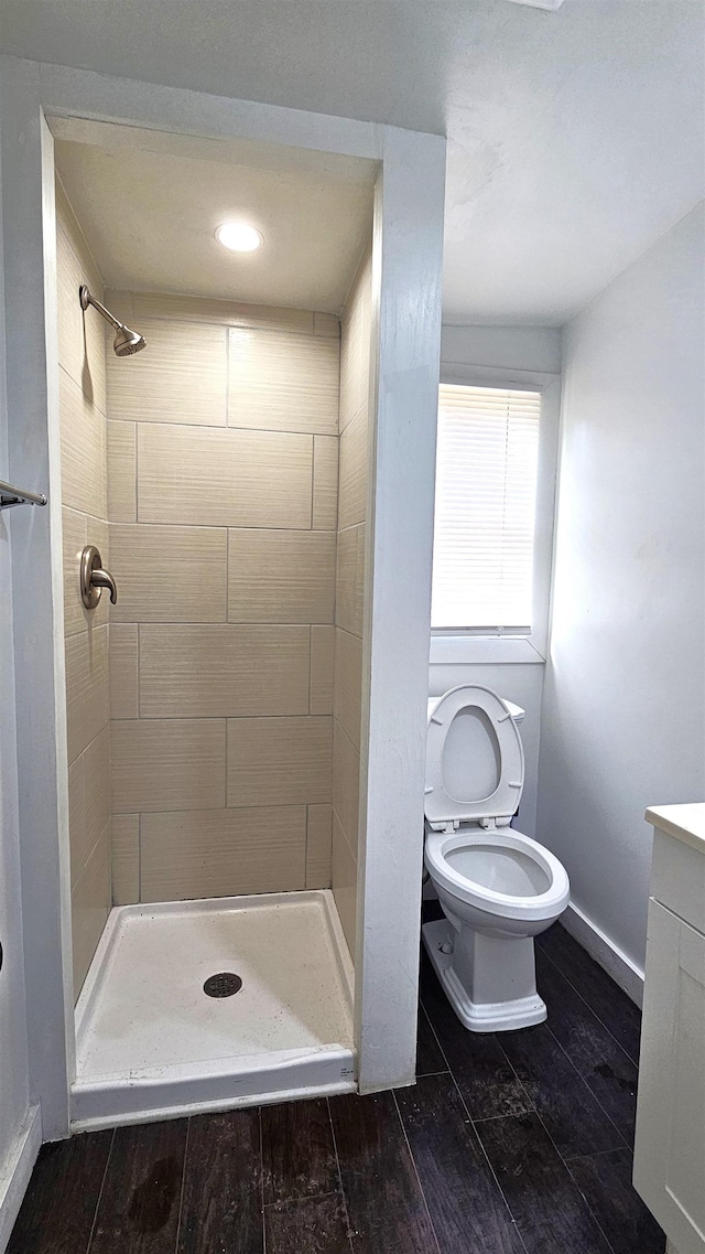 bathroom featuring a shower stall, baseboards, toilet, wood finished floors, and vanity