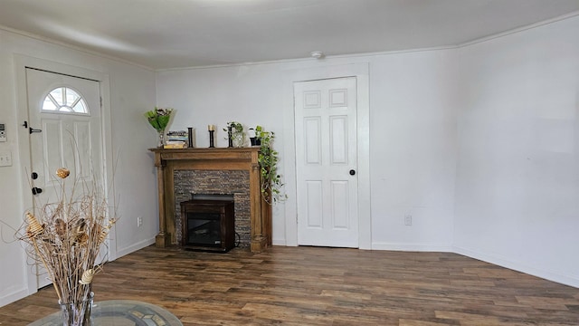living room featuring a glass covered fireplace, baseboards, wood finished floors, and ornamental molding