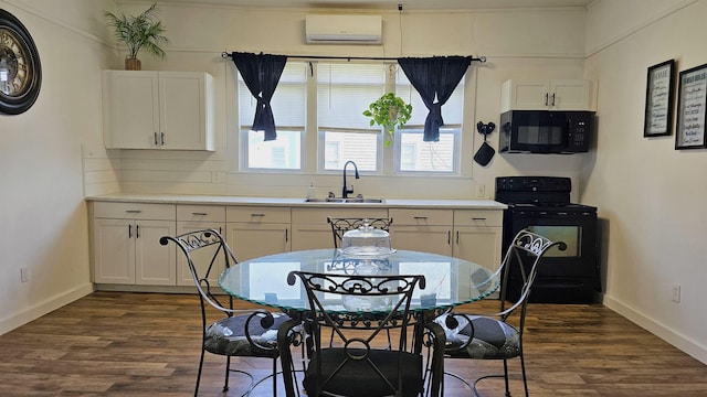 kitchen featuring a wall mounted air conditioner, dark wood-style floors, white cabinets, black appliances, and a sink