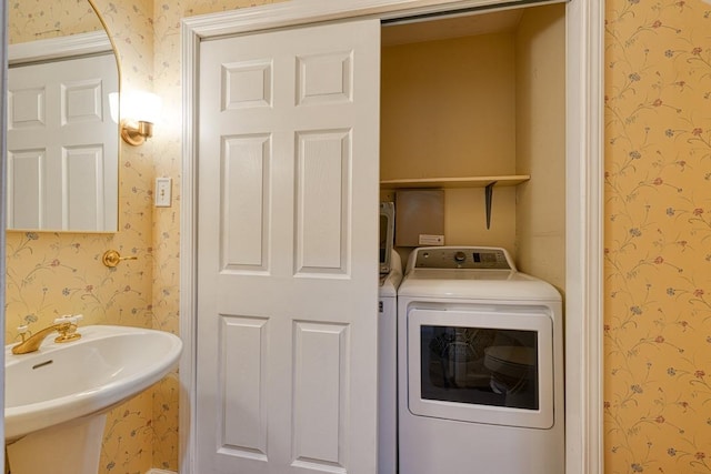 laundry area with laundry area, washer / clothes dryer, wallpapered walls, and a sink