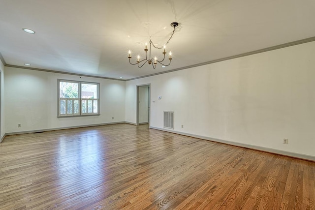 unfurnished room with wood finished floors, baseboards, visible vents, ornamental molding, and a chandelier