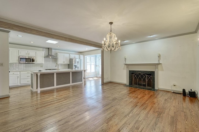 unfurnished living room featuring baseboards, a premium fireplace, an inviting chandelier, light wood-style flooring, and crown molding