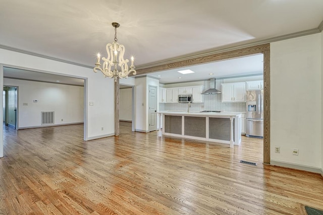 unfurnished living room with baseboards, visible vents, ornamental molding, light wood-style floors, and a notable chandelier