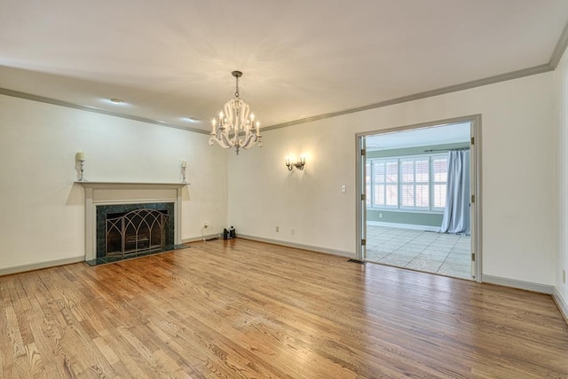 unfurnished living room with a high end fireplace, a notable chandelier, crown molding, and wood finished floors
