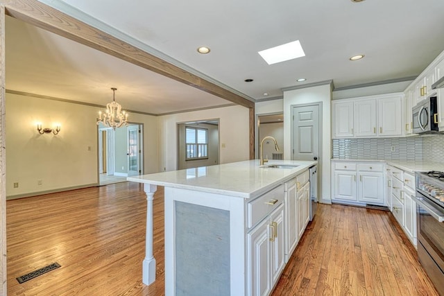 kitchen featuring visible vents, a notable chandelier, a sink, appliances with stainless steel finishes, and a skylight