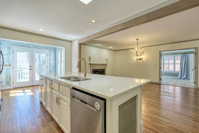 kitchen featuring light wood-type flooring, a sink, open floor plan, crown molding, and dishwasher