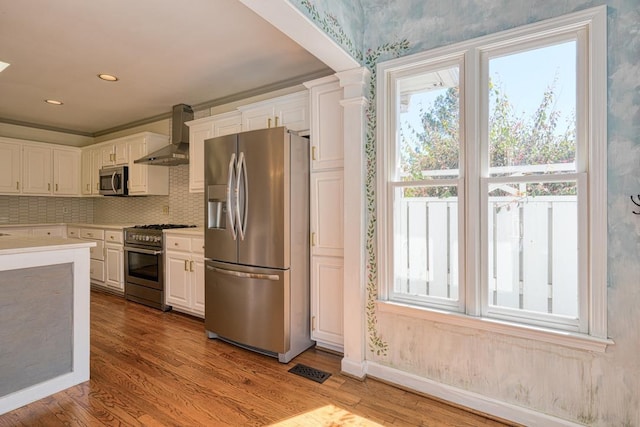 kitchen with white cabinets, stainless steel appliances, and wall chimney range hood