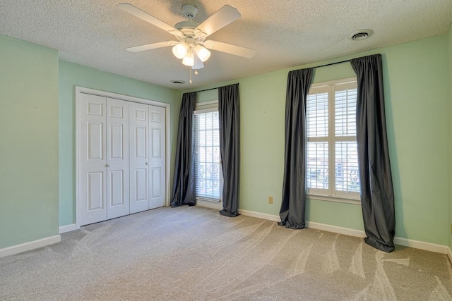 unfurnished bedroom with multiple windows, carpet flooring, baseboards, and visible vents