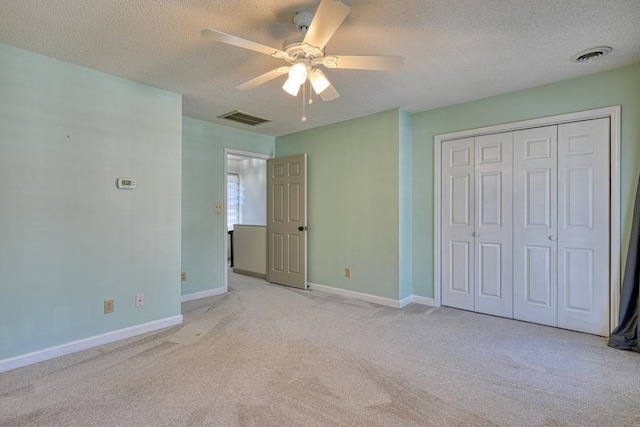 unfurnished bedroom with visible vents, baseboards, a textured ceiling, and light colored carpet