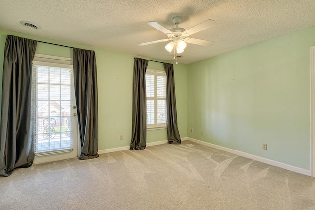 unfurnished room featuring visible vents, baseboards, ceiling fan, light carpet, and a textured ceiling